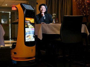 In this photo taken on Dec. 17, 2021, Mekong Asian Cuisine owner Winnie Zhang shows off the restaurant's newest waiter - a robot called KettyBot that delivers dishes to patrons at their table and can even sing Happy Birthday. The robot, which retails for about $15,000, is the first of its kind in Ottawa, and allows for contactless service.