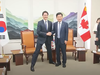 A screenshot from a report by South Korea's Yonhap News Agency showing Prime Minister Justin Trudeau adopting an unusually wide stance while posing with Korean National Assembly speaker Kim Jin-pyo.