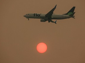 A Flair Airlines Boeing 737 descends through forest fire smoke as the sun rises in Calgary on Tuesday, May 16, 2023.