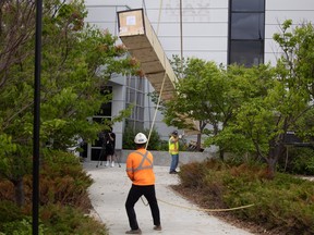 Crews help lift a nearly two thousand pound IMAX screen into the Kramer IMAX theatre