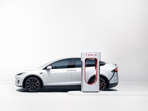 A Tesla charges at a proprietary charger
