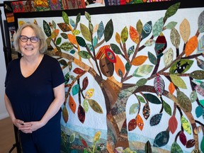 Regina's Judy Cormier stands next to a quilt.