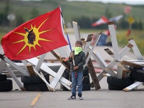 A young child carries a flag at a road block at Brady Road Landfill on Tuesday, July 11, 2023, as part of a protest against Manitoba Premier Heather Stefanson's decision to not search for murder victims. (Chris Procaylo/Postmedia)