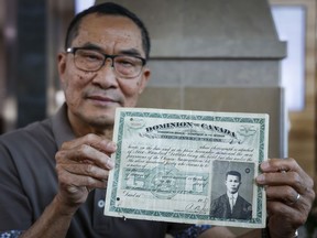Matthew Yan holds his father's identification certificate from 1920, showing he had paid a $500 head tax, in Calgary, Friday, June 30, 2023.THE CANADIAN PRESS/Jeff McIntosh
