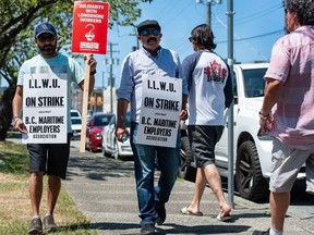 Striking port workers belonging to the International Longshore and Warehouse Union Canada walk the picket line near the Port of Vancouver's Clark Drive entrance in VancouverJuly 1, 2023.