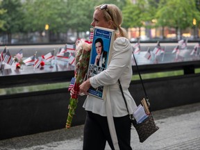 Diane walks with a picture of her former husband Michael Massaroli as people visit the 9/11 Memorial at the Ground Zero site in lower Manhattan as the nation commemorates the 22nd anniversary of the attacks on September 11, 2023 in New York City. (Photo by Spencer Platt/Getty Images)