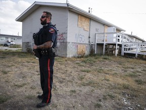 Blood Tribe Police Service Const. Manasse Gabor stands outside of a boarded up house in Standoff, Alta., on Friday, Aug. 25, 2023.