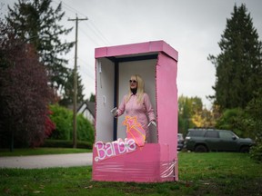 Anne Bruinn stands dressed as a Barbie doll inside a box in an attempt to entertain motorists driving past her home in Vancouver, on Thursday, October 19, 2023. The would-be Mrs. Dressup, who regularly dresses up as a variety of characters to greet people, likes to call herself the "queen of the cosplay corner," referencing the performance art of costume play.