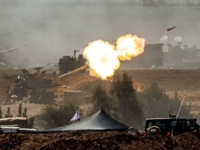 An Israeli army M109 155mm self-propelled howitzer fires rounds near the border with Gaza in southern Israel on October 12, 2023.