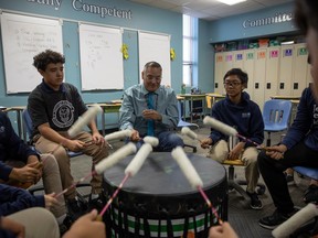 Teacher Evan Whitestar sits with students during their Grade 8 drum class at Mother Teresa Middle School.