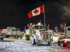 Anti-COVID-19 vaccine mandate demonstrators gather as a truck convoy blocks the highway at the U.S. border crossing in Coutts, Alta., on Feb. 1, 2022. An internal RCMP review of the force's response to "Freedom Convoy" protests found that some officers at the scene of an Alberta blockade were not told of threats to harm police until after the episode ended.