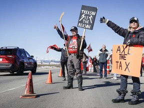 Anti-carbon levy protesters wave signs and chant slogans as they block a westbound lane of the Trans-Canada highway near Cochrane, Alta., Monday, April 1, 2024.