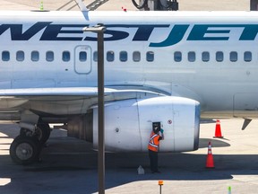 A WestJet technical operations employee does some maintenance work on a Boeing 737 engine at the Calgary International Airport on Wednesday June 26, 2024.