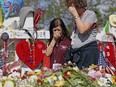 Marjory Stoneman Douglas High School administrative employees Margarita LaSalle, left, and JoEllen Berman, walk along the hill near the school lined with 17 crosses to honor the students and teachers killed on Valentine's Day. Teachers and staff returned to the school, Friday, February 23, 2018, for an orientation and to get ready to receive students next week.  (Charles Trainor Jr/The Miami Herald via AP)