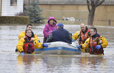 Members of the Chatham-Kent fire service dive team help residents whose homes were flooded in Chatham. (Louis Pin/Postmedia News)
