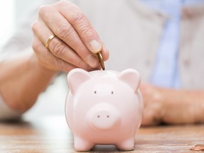 Stock photo illustration on savings, money, annuity insurance, retirement and people concept - close up of senior woman hand putting coin into piggy bank. Getty Images/iStock Photo