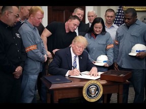 WASHINGTON, DC - MARCH 08: Surrounded by steel and aluminum workers, U.S. President Donald Trump (C) signs a 'Section 232 Proclamation' on steel imports during a ceremony in Roosevelt Room the the White House March 8, 2018 in Washington, DC. Trump signed proclamations that will impose a 25-percent tarriff on imported steel and a 10-percent tarriff on imported alumninum.