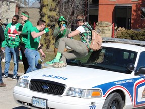 A man poses on a police cruiser while his friend takes a photograph on Saturday in London. Police were busy clearing out house parties on St. Patrick's Day. DALE CARRUTHERS / THE LONDON FREE PRESS