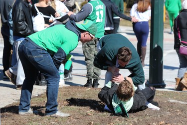 Two friends wrestle on the grass on Saturday. London police were busy clearing out house parties around Western University and the downtown area for St. Patrick's Day. DALE CARRUTHERS / THE LONDON FREE PRESS