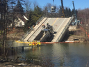 Workers start the process of removing a dump truck from the collapsed Port Bruce bridge Monday. It's been stuck there since the span fell during heavy flooding last month.