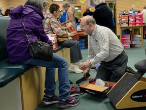 Jeff Seigel, above, helps a customer with shoes Thursday at J. Seigel Footwear Inc. Seigel, the third generation of his family to sell shoes in London, is retiring, news that caused lineups of customers outside the store on Highbury Avenue. (MORRIS LAMONT, The London Free Press)