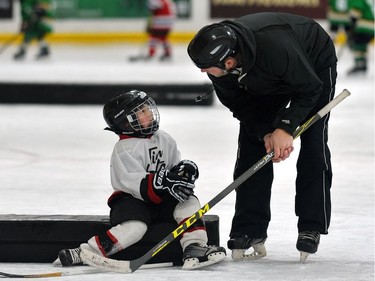 A coach helps one of his players during a game of initiation level hockey at Oakridge arena.  MORRIS LAMONT/THE LONDON FREE PRESS /POSTMEDIA NETWORK