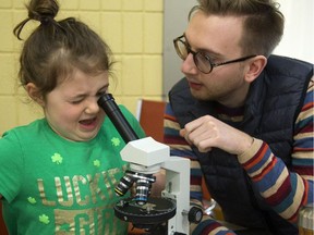 Emily Dynes, 5, of London, has to stretch to get a good look down a microscope Sunday at the Children’s Museum. Patrick Hill, an earth sciences major at Western, tells Emily she’s looking at a very, very, very thin slice of a chondritic meteorite, thought to be like the one that fell near Grand Bend earlier this year. Hill says the meteorite came from the asteroid belt left over from the origin of our solar system. (Mike Hensen/The London Free Press)