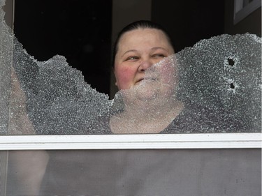 Cindy, a resident at 309 Marconi Blvd. who declined to give her last name, stands in her open front door behind the glass of a screen door shattered by a shotgun blast early Tuesday morning. 
Derek Ruttan/The London Free Press