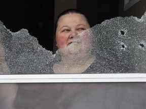 Cindy, who didn't want her last name used, looks out the shattered front door of her Marconi Boulevard home. The door was hit with a shotgun blast in the early hours of Tuesday March 13, 2018. (Derek Ruttan/The London Free Press)