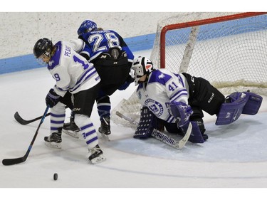 Western Mustangs defenceman Emma Pearson holds off  Montreal Carabins forward Catharine Dubois while clearing the rebound in front of goaltender Camen Lasis during their game in the Women's Hockey National Championship at Western University's Thompson Arena on Thursday. (MORRIS LAMONT/THE LONDON FREE PRESS)