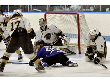 Western Mustangs Amanda Pereira is knocked to the ice by Manitoba Bisons defenders Erica Reider, left, and Jenai Buchanan in front of goaltender Lauren Tarashuk during the Women's Hockey National Championship gold medal game. Western lost 2-0 to the Manitoba Bisons at Western University's Thompson Arena on Sunday. MORRIS LAMONT/THE LONDON FREE PRESS /POSTMEDIA NETWORK