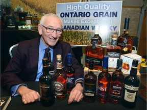 Jan Westcott, president and CEO of the Association of Canadian Distillers, sits amid a display of whiskeys made from Ontario grains at the Convention of the Grain Growers of Ontario in London. (MORRIS LAMONT/THE LONDON FREE PRESS)