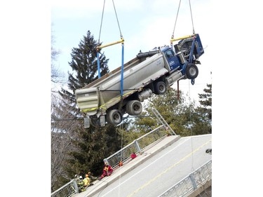 Workers watch on Friday, March 23, as a crane lifts a dump truck that was stuck for weeks on a collapsed bridge near Port Bruce. Derek Ruttan/The London Free Press