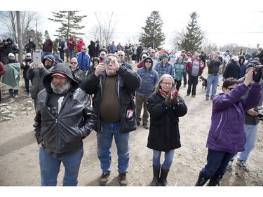 Hundreds of people gathered to watch a crane lift a stranded dump truck from a collapsed bridge, in Port Bruce on Friday March 23. Derek Ruttan/The London Free Press