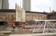 Chris Oquinn of Tricar holds onto a section of wall form being moved by the crane at the site of their new building on York Street in London, Ont. The forms are made with a steel frame but a plastic face reinforced by metal that allows the forms to last much longer than plywood, as the plastic doesn't absorb moisture from the wet concrete like wood would. (MIKE HENSEN, The London Free Press)