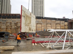 Chris Oquinn of Tricar holds onto a section of wall form being moved by the crane at the site of their new building on York Street in London, Ont. The forms are made with a steel frame but a plastic face reinforced by metal that allows the forms to last much longer than plywood, as the plastic doesn't absorb moisture from the wet concrete like wood would. (MIKE HENSEN, The London Free Press)