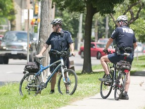 Two police officers on bikes stand on Queens Avenue between Adelaide and William Streets. (File photo)