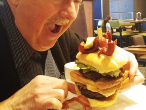 Writer Jim Fox prepares to tackle the monstrous Holy Cow Burger that’s a handful and a mouthful at the Simcoe Yard House, which is situated in Casino Rama near Orillia. (Barbara Fox, Special to Postmedia News)