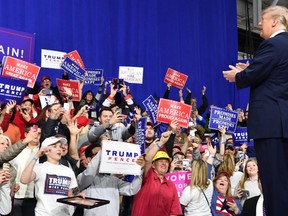 At a March rally in Pennsylvania, U.S. President Donald Trump greets supporters carrying signs that hit on many of themes he has emphasized in his presidency.
Nicholas Kamm/AFP/Getty Images