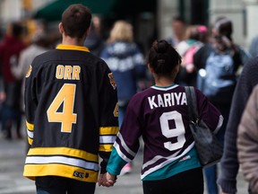 A man wearing a Boston Bruins jersey and a woman wearing an Anaheim Ducks jersey in tribute to the victims of the Humboldt Broncos bus crash, walk in downtown Vancouver, B.C., on Thursday. Darryl Dyck/The Canadian Press