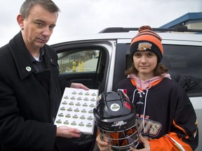 Shawn Lewis, team manager for the London Bandits minor bantam team, puts a Humboldt Broncos sticker on the helmet of his nephew, Ethan Wilkins, 13. Players on the 68 teams competing this weekend during the Ontario Alliance hockey finals will wear the stickers in tribute to the Broncos. (Mike Hensen/The London Free Press)