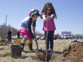 Sydney Rowe (9) (Left) and Katelyn Dunn (5), of the 110th Brownies/Girl Guides, team up to plant a tree at St. Julien Park in London, Ont. on Sunday April 22, 2018. Hundreds of people attended an Earth Day celebration at the park where the Upper Thames River Conservation Authority engaged volunteers to help plant 600 trees. Derek Ruttan/The London Free Press/Postmedia Network