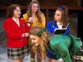 Holly Holden (as Heather Duke) bends over to form a desk for Shae Solomon (Veronica) to write a forged letter in the Original Kids production of Heathers: High School Edition. Dictating the letter is Olivia Ho as Heather Chandler, and in yellow is Abby Benjaminsen as Heather McNamara. (MIKE HENSEN, The London Free Press)