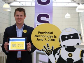 Landon Tulk, vice-president of finance for the Ontario Undergraduate Student Alliance (OUSA) shows off the Pledge to Vote website on a tablet, while standing beside Election Ontario's "AskOwen.ca" robot. (Shannon Coulter/The London Free Press)
