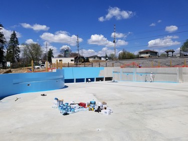 Painters apply coats of blue paint to the sides of the new wave pool.