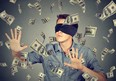 Blindfolded young businessman trying to catch dollar bills banknotes flying in the air isolated on gray wall background. Financial corporate success or crisis challenge concept