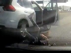 In this image taken from a video, a woman is seen tumbling from a white SUV on Hwy. 401
