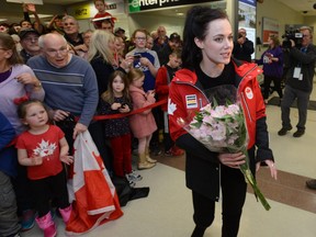 Tessa Virtue with flowers given to her by a fan after arriving at London International Airport back from the Olympic games where they won gold in the ice dance. (MORRIS LAMONT/THE LONDON FREE PRESS)