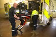 Middlesex-London EMS paramedics Don Black and Samantha Quinlan pull a stretcher from an ambulance.  (Mike Hensen/The London Free Press)