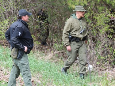 OPP officers search a wooded area Friday on Front Road, about two kilometres north of Vanastra, where a body was found on Thursday. (DALE CARRUTHERS / THE LONDON FREE PRESS)